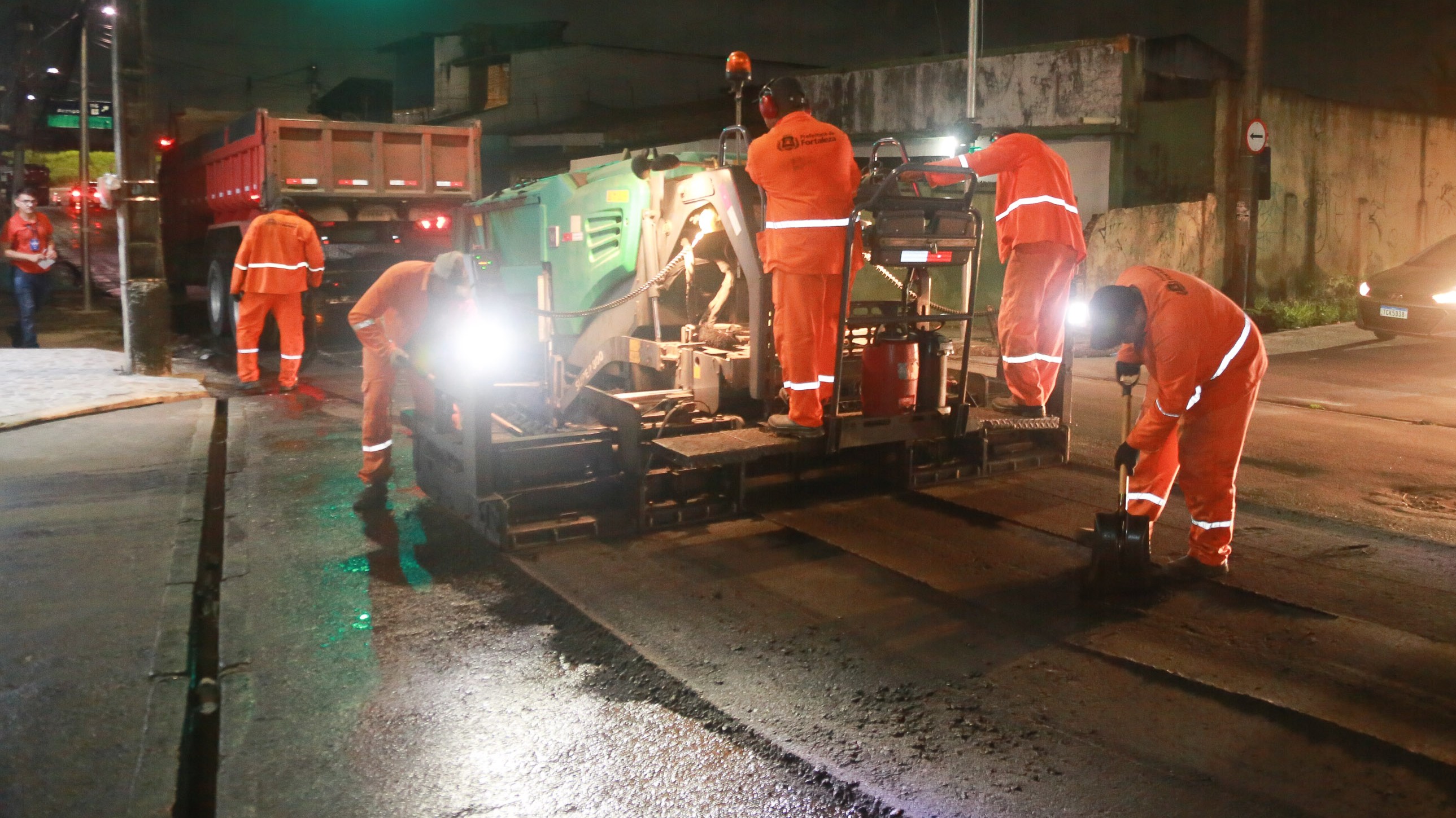 homens trabalhando no recapeamento de uma rua no período da noite